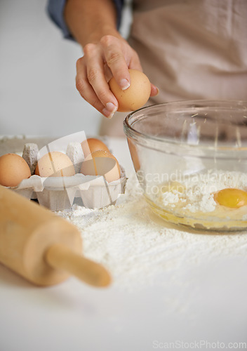 Image of To make a cake you have to break a few eggs. Closeup shot of a woman putting ingredients into a bowl in her kitchen.