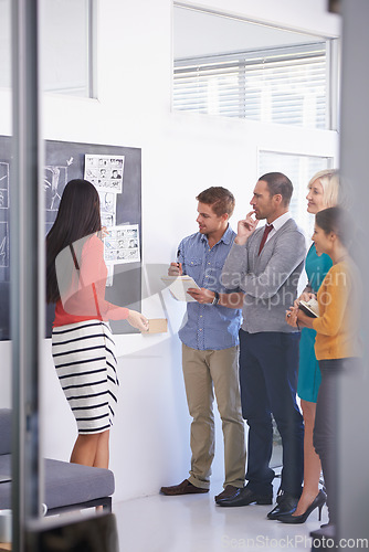 Image of Shes full of great ideas. A businesswoman standing and presenting a storyboard to his team in an office.