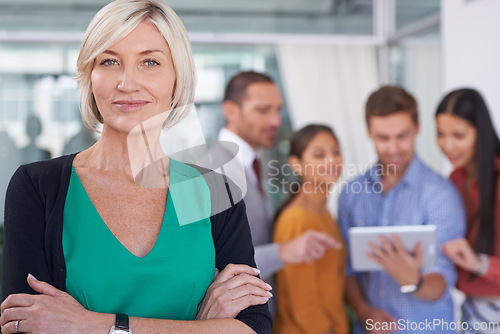 Image of True leaders dont create followers... They create more leaders. A portrait of a middle-aged businesswoman standing in an office with her coworkers in the background.