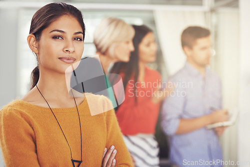 Image of Ive got confidence in my teams ability to succeed. Cropped portrait of a young businesswoman standing in an office with her team in the background.