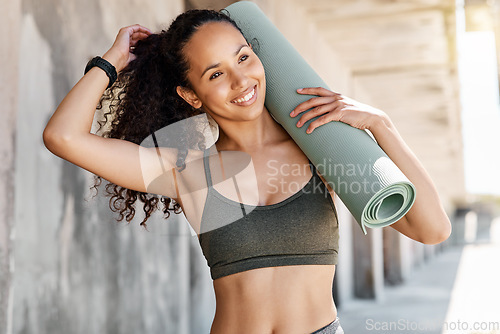 Image of Im at my happiest when Im healthy. an attractive young woman standing and holding a yoga mat while tying her hair during her outdoor workout.