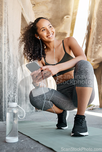 Image of I love seeing good health stats. Full length shot of an attractive young woman crouching down and using her cellphone during her outdoor workout.