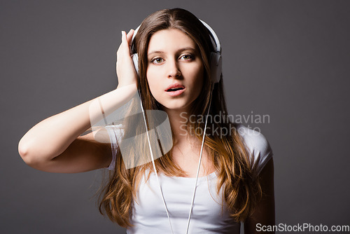 Image of Music is art that speaks to the heart. a young woman listening to music against a studio background.