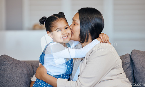 Image of Mixed race woman kissing her adorable little daughter on the cheek while bonding together at home. Small girl feeling special and looking happy to be getting love, affection and quality time with mom