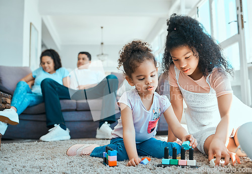 Image of We prefer building new toys. two sister playing on the floor while their parents relax in the background.