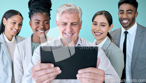 Image of Snapping pics with the team. Studio shot of a diverse group of corporate businesspeople using a tablet to take selfies against a blue background.