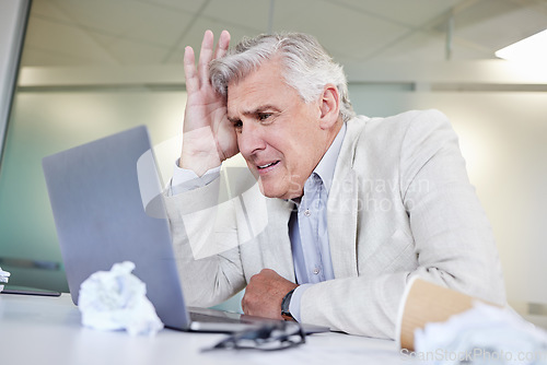 Image of Will this be done today. a mature businessman looking overwhelmed while using a laptop in an office at work.