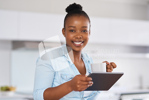 Image of Staying in the know is easy with the internet. a woman drinking coffee while using a digital tablet at home.