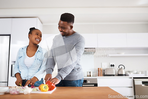 Image of I love how youre always helping around the house. a young couple cooking together at home.