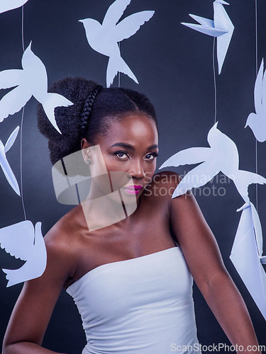 Image of Be the most dazzling version of yourself. Studio portrait of a beautiful young woman posing with paper birds against a black background.
