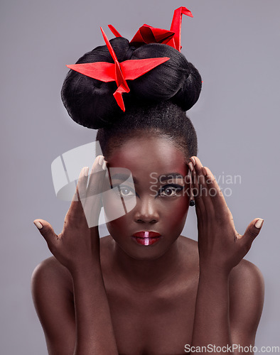 Image of Theres boundless creativity with makeup. Studio portrait of a beautiful young woman wearing Asian inspired makeup and posing with origami against a grey background.