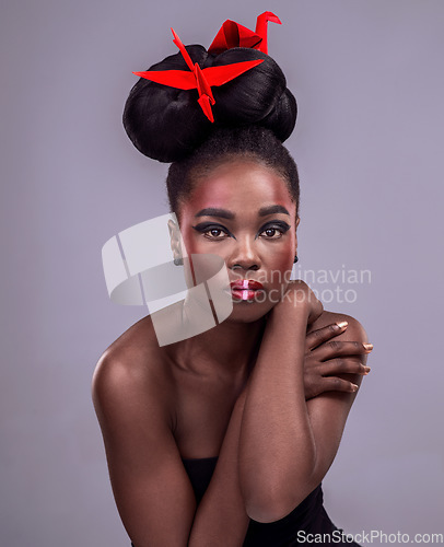 Image of Unafraid to be me. Studio portrait of a beautiful young woman wearing Asian inspired makeup and posing with origami against a grey background.