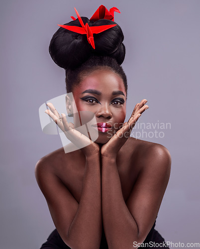 Image of Glow is the essence of beauty. Studio portrait of a beautiful young woman wearing Asian inspired makeup and posing with origami against a grey background.