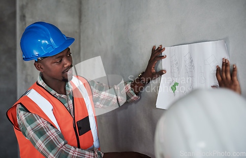 Image of Teamwork makes the construction project work. a young man and woman going over building plans at a construction site.