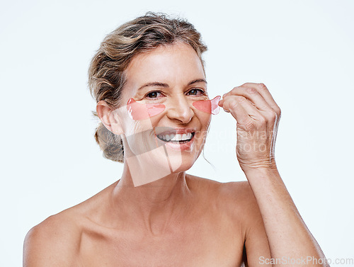 Image of Lets do a little reversing. a mature woman wearing under-eye gel patches while posing against a white background.