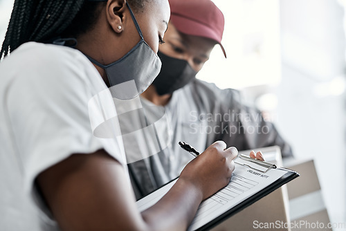 Image of Right on time as promised. a masked young woman signing for a delivery received at home.