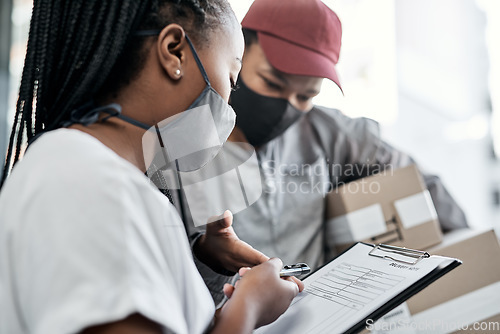 Image of Nothing satisfies a customer like same day delivery. a masked young woman signing for a delivery received at home.