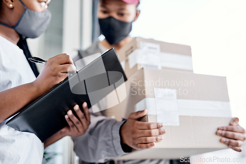 Image of A five star rating for an excellent delivery service. a masked young woman signing for a delivery received at home.