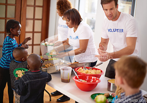 Image of Making sure they get a healthy meal. volunteers serving food to a group of little children.