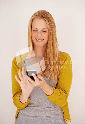 Image of Downloading a new app is so easy. a happy woman sending a text message on her mobile phone.