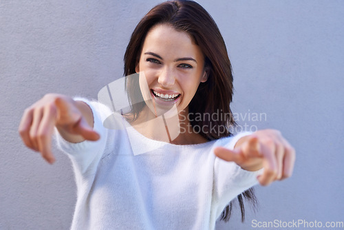 Image of Thats how I roll. Portrait of a happy young woman standing against a gray background and pointing to the camera.