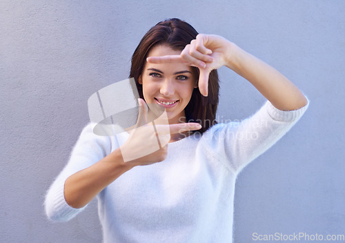 Image of See things from a different perspective. Portrait of an attractive young woman standing against a gray background and making a finger frame.