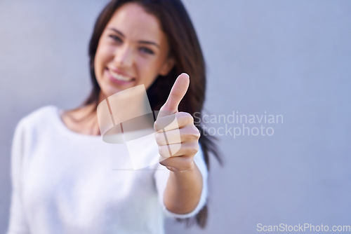 Image of Youre always a winner in my books. Portrait of a happy young woman standing against a gray background and giving thumbs up.