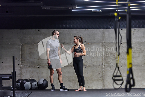 Image of Muscular man and fit woman in a conversation before commencing their training session in a modern gym.