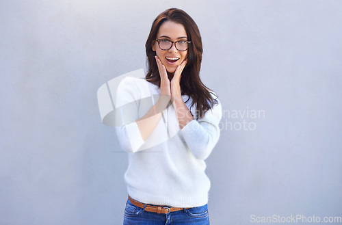 Image of Wow I love your look. Portrait of an attractive young woman standing against a gray background looking surprised.