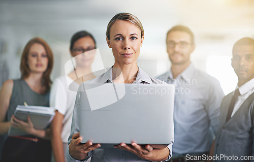 Image of I present to you...Portrait of a businesswoman holding a laptop with her colleagues blurred in the background.