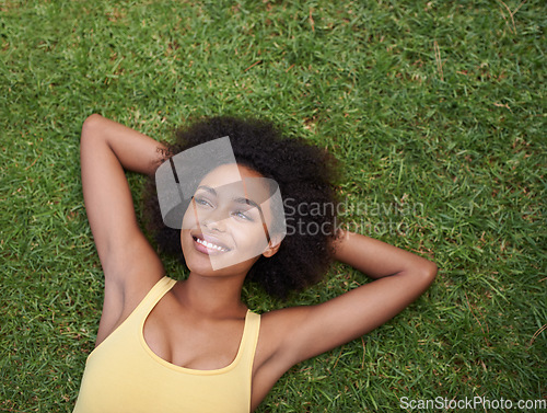 Image of Planning the rest of her lazy day. a happy young woman lying on the grass.