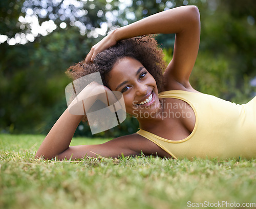 Image of Hanging out in the park. Portrait of a happy young woman lying on the grass in a park.