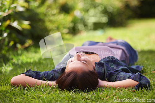 Image of Do not disturb. an attractive young woman lying on the grass.