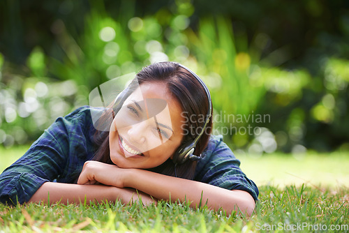 Image of The best way to spend a sunny afternoon. Portrait of an attractive young woman lying on the grass and listening to music.