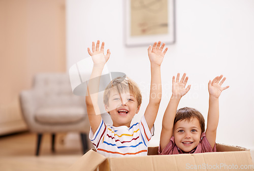 Image of Lets give mom the best present. Two young brothers raising their arms as they jump out of a cardboard box.