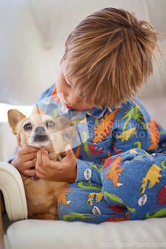 Image of Growing together, loving together. A little boy petting his dog on the couch.