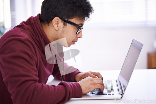 Image of No distractions because Im hard at work. a handsome young man working on his laptop in an office.