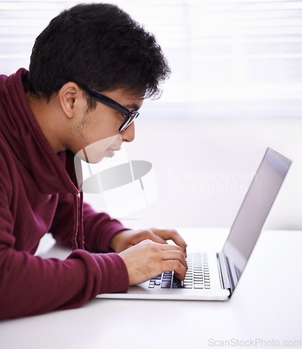Image of Getting the task done efficiently. a handsome young man working on his laptop in an office.