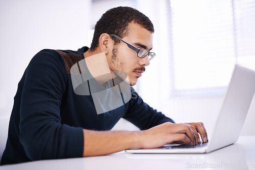 Image of Blazing through lines of code with ease. a handsome young man working on his laptop in an office.