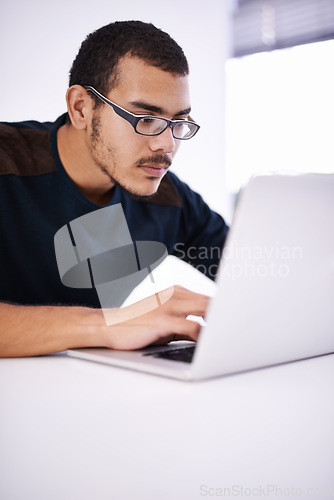 Image of Working hard on a brand new design. a handsome young man working on his laptop in an office.