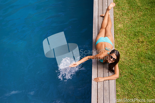 Image of By the pool - my favorite place to be. Portrait of a beautiful young woman relaxing by a swimming pool.