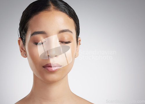 Image of A beautiful young mixed race woman with glowing skin posing against grey copyspace background. Hispanic woman with natural looking eyelash extensions finds inner peace in a studio