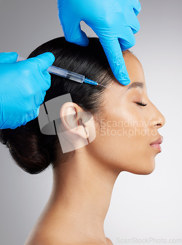 Image of Closeup of a gorgeous mixed race woman getting botox filler. Hispanic model getting filler to reduce wrinkles against a grey copyspace background in a studio