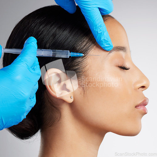 Image of Closeup of a gorgeous mixed race woman getting botox filler. Hispanic model getting filler to reduce wrinkles against a grey copyspace background in a studio