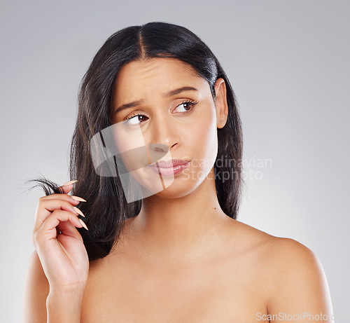 Image of What am I to do. an attractive young woman looking unhappy with her hair in studio against a grey background.