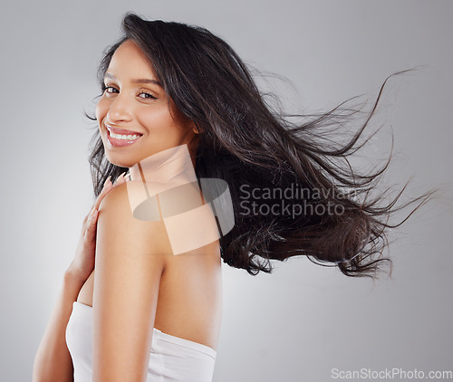 Image of Sleek, smooth and glossy hair. Cropped portrait of an attractive young woman posing in studio against a grey background.