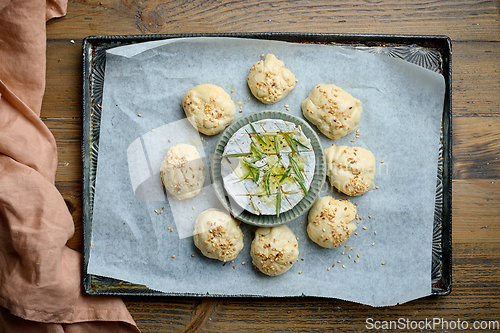 Image of raw yeast dough buns and brie cheese