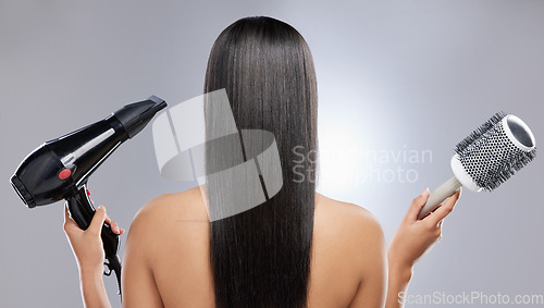 Image of Volume or no volume. Rearview shot of a woman with sleek hair holding a hairdryer and blow-dry brush.