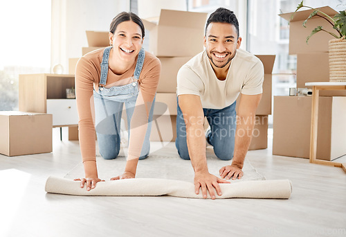 Image of This is where we make an exciting new start. Portrait of a young couple rolling out a carpet together in their new home.