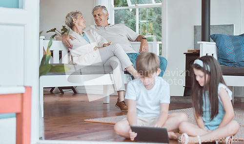 Image of Babysitting made easy. a brother and sister bonding while using a digital tablet together with their grandparents in the background.